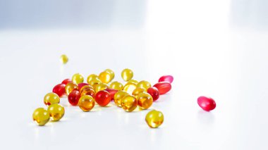 Farklı şekillerdeki şeffaf kapsüllerdeki vitaminler ve ilaçlar beyaz arka plan, kırmızı ve sarı kapsüller, beslenme takviyeleri, ilaçlar ve vitaminler üzerinde yatmaktadır. Ayır, makro
