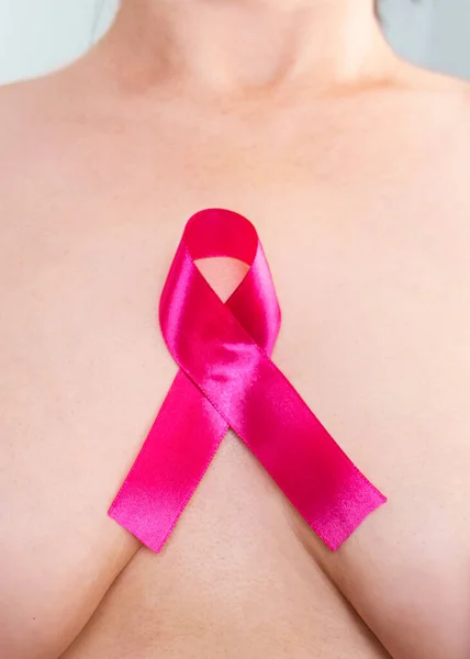 World Breast Cancer Day. prevention of breast cancer. Female breast with a pink ribbon as a symbol.