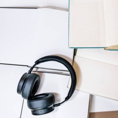 Online eğitim konsepti. Sesli kitap okuma konsepti. Kitap okumayı severim. Siyah kablosuz kulaklıklar açık kitaplarda yatar..