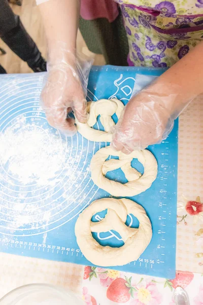 Hamurdan kraker pişirmek simit şekli yaratıyor. Brezel testi. Hamur pişirme, seçici odaklanma.