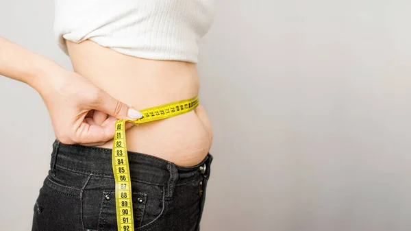 woman makes a measurement of the waist with a centimeter tape, waist,fat 