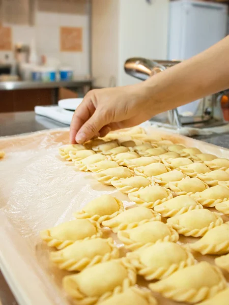 hands spread dumplings or ravioli on a tray in the kitchen, cooking dumplings, hand molding