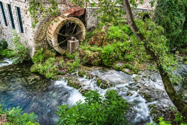 Yunanistan 'ın Livadia kentinde, paslı tekerleği olan eski bir su değirmeninin kalıntılarının yanında bir dağ deresi akıyor..