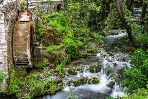 古い水車小屋の遺跡の近くにリヴァディアのギリシャの町の中心部に渓流が流れています — ストック写真