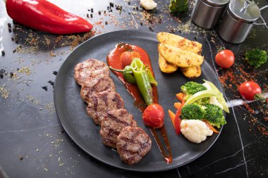 Izgara köfte, patates ve sebzeli servis tabağı.