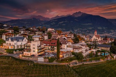 Tirol, İtalya - Bolsano şehrinin kuzeybatısında gün batımında güzel gökyüzü, bulutlar, üzüm bağları ve İtalyan Dolomitleri ile yer alan bir komün.