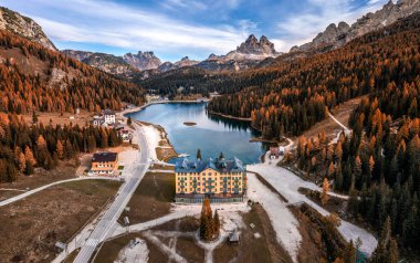 Misurina, Auronzo, İtalya - Bir sonbahar sabahı Tre Cime di Lavaredo tepeleri (Üç Merlon), sonbahar yaprakları ve mavi sabah gökyüzü ve bulutları ile İtalyan Dolomitlerindeki Misurina Gölü 'nün havadan görünüşü