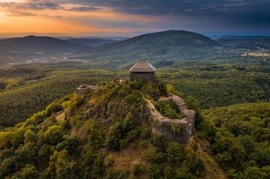 Salgotarjan, Hungary - Aerial view of Salgo Castle (Salgo vara) in Nograd county with dark storm clouds and golden sunset sky on a summer afternoon