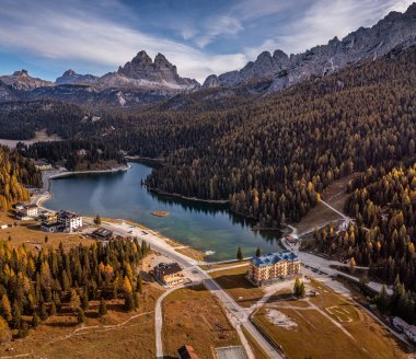 Misurina, Auronzo, İtalya - Bir sonbahar sabahı Tre Cime di Lavaredo tepeleri (Üç Merlon), sonbahar yaprakları ve mavi sabah gökyüzü ve bulutları ile İtalyan Dolomitlerindeki Misurina Gölü 'nün havadan görünüşü