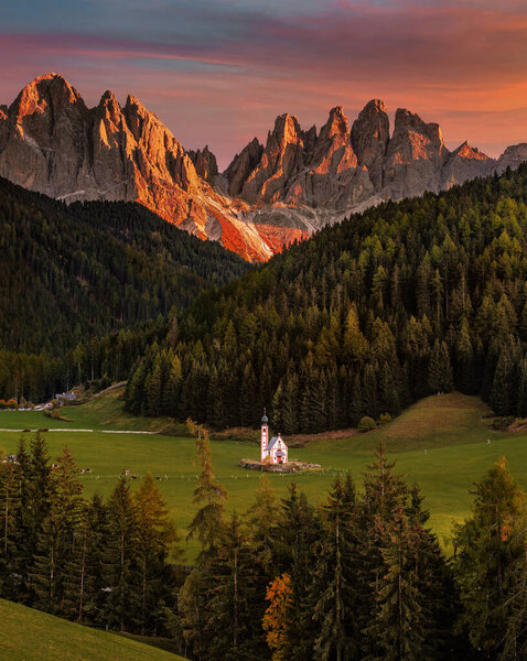 Val Di Funes, Dolomites, Italy - The beautiful St. Johann Church at South Tyrol with the Italian Dolomites and spectacular colorful sunset at background on a warm autumn afternoon