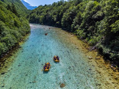 Soca Vadisi, Slovenya - Parlak güneşli bir yaz gününde yeşil yapraklarla nehirden geçen rafting botlarıyla zümrüt Alp Nehri 'nin havadan görünüşü. Slovenya 'da rafting