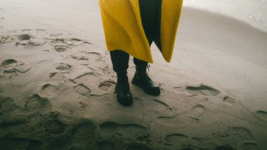 Plajda siyah botlarla yürüyorum.