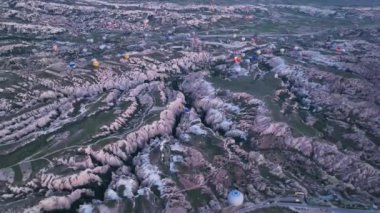 hot air balloons fly over the mountainous landscape of Cappadocia, Turkey. Aerial view