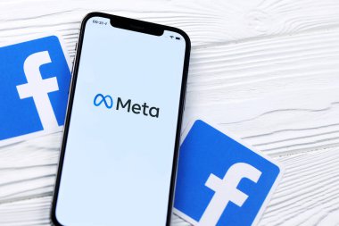 KHARKOV, UKRAINE - 29 Ekim 2021: Meta veya MetaVerse logosu olan Iphone 12 Pro, iki kağıttan Facebook logosu olan ahşap masa üzerinde bulunuyor.
