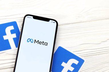 KHARKOV, UKRAINE - 29 Ekim 2021: Meta veya MetaVerse logosu olan Iphone 12 Pro, iki kağıttan Facebook logosu olan ahşap masa üzerinde bulunuyor.