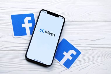 KHARKOV, UKRAINE - 29 Ekim 2021: Meta veya MetaVerse logosu olan Iphone 12 Pro, iki kağıttan Facebook logosu olan ahşap masa üzerinde bulunuyor.