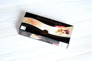 KHARKOV, UKRAINE - 19 Nisan 2021: Henry Lambertz Mozart-Kugeln lüks siyah çikolata şekerlemeleri beyaz ahşap masa üzerindeki kara kutuda