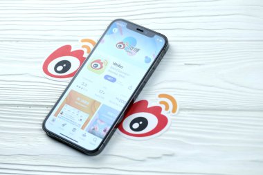KHARKOV, UKRAINE - 5 Mart 2021: Sina Weibo simgesi ve uygulaması iPhone 12 'den beyaz ahşap masadaki profesyonel ekranda