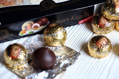 KHARKOV, UKRAINE - 19 Nisan 2021: Henry Lambertz Mozart-Kugeln lüks siyah çikolata şekerlemeleri beyaz ahşap masa üzerindeki kara kutuda