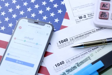 KHARKOV, UKRAINE - 5 Mart 2021: Turbotax sezgi web sitesi iPhone 12 profesyonel ekranda 1040 ve w-2 ABD bayrağında kağıt vergi formları