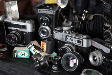 KHARKOV, UKRAINE - 27 Nisan 2021: Fotoğraf makineleri ve fotoğrafçı karanlık odasındaki siyah ahşap masada eski bir fotoğraf makinesi. Sovyetler Birliği zamanından fotoğraf malzemeleri.