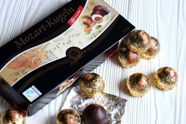 KHARKOV, UKRAINE - 19 Nisan 2021: Henry Lambertz Mozart-Kugeln lüks siyah çikolata şekerlemeleri beyaz ahşap masa üzerindeki kara kutuda