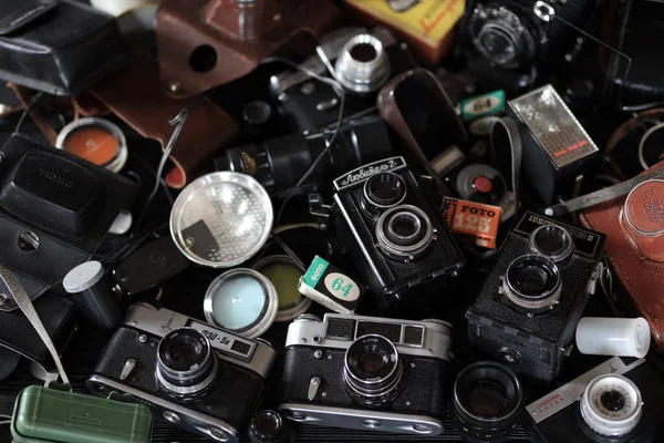 KHARKOV, UKRAINE - 27 Nisan 2021: Fotoğraf makineleri ve fotoğrafçı karanlık odasındaki siyah ahşap masada eski bir fotoğraf makinesi. Sovyetler Birliği zamanından fotoğraf malzemeleri.