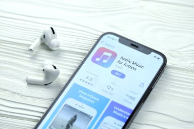 KHARKOV, UKRAINE - 5 Mart 2021: Sanatçı simgesi ve uygulaması için Apple müziği iPhone 12 profesyonel ekranda beyaz ahşap masa uzmanıyla birlikte