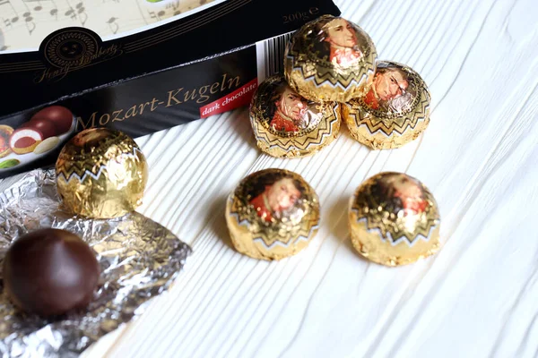 KHARKOV, UKRAINE - 19 Nisan 2021: Henry Lambertz Mozart-Kugeln lüks siyah çikolata şekerlemeleri beyaz ahşap masa üzerindeki kara kutuda