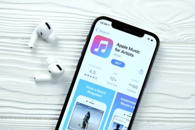 KHARKOV, UKRAINE - 5 Mart 2021: Sanatçı simgesi ve uygulaması için Apple müziği iPhone 12 profesyonel ekranda beyaz ahşap masa uzmanıyla birlikte