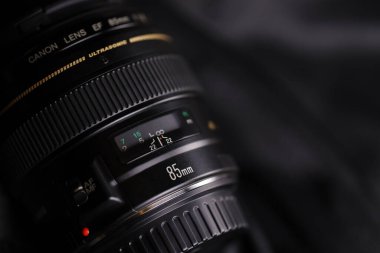 KHARKOV, UKRAINE - 21 Ocak 2021: Siyah kumaş zemin üzerinde Canon EF 85mm 1.8 lens. Canon marka ürününün ayrıntılı fotoğrafı