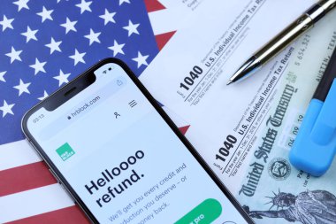 KHARKOV, UKRAINE - 5 Mart 2021: HR Bloğu web sitesi iPhone 12 profesyonel ekranda 1040 ve W-2 kağıt vergi formları ABD bayrağında