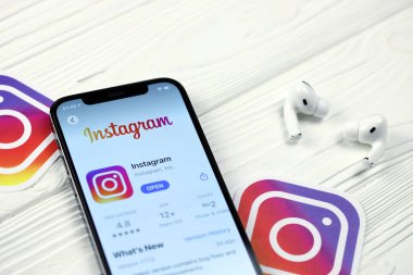 KHARKOV, UKRAINE - 5 Mart 2021: Instagram simgesi ve uygulaması iPhone 12 'deki profosyonel ekranda beyaz ahşap masadaki hava podları profosyoneli
