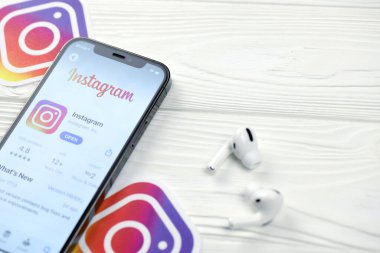 KHARKOV, UKRAINE - 5 Mart 2021: Instagram simgesi ve uygulaması iPhone 12 'deki profosyonel ekranda beyaz ahşap masadaki hava podları profosyoneli