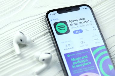 KHARKOV, UKRAINE - 5 Mart 2021: iPhone 12 'deki Uygulama mağazasından gelen simge ve uygulamayı beyaz ahşap masadaki uçak podları profesyoneli ile birlikte ekranda şımart
