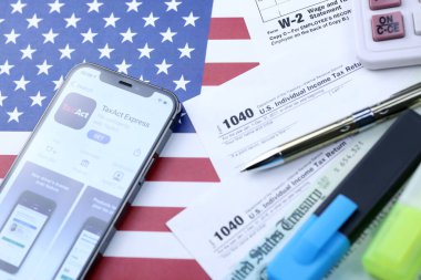 KHARKOV, UKRAINE - 5 Mart 2021: Vergilendirme ekspres uygulaması iPhone 12 profesyonel ekranda 1040 ve W-2 ABD bayrağında kağıt vergisi formları