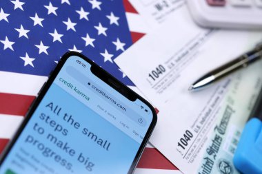 KHARKOV, UKRAINE - 5 Mart 2021: ABD bayrağında 1040 ve w-2 kağıt vergi formlarıyla iPhone 12 profesyonel ekranda kredi karması web sitesi
