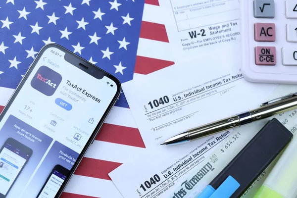 KHARKOV, UKRAINE - 5 Mart 2021: Vergilendirme ekspres uygulaması iPhone 12 profesyonel ekranda 1040 ve W-2 ABD bayrağında kağıt vergisi formları