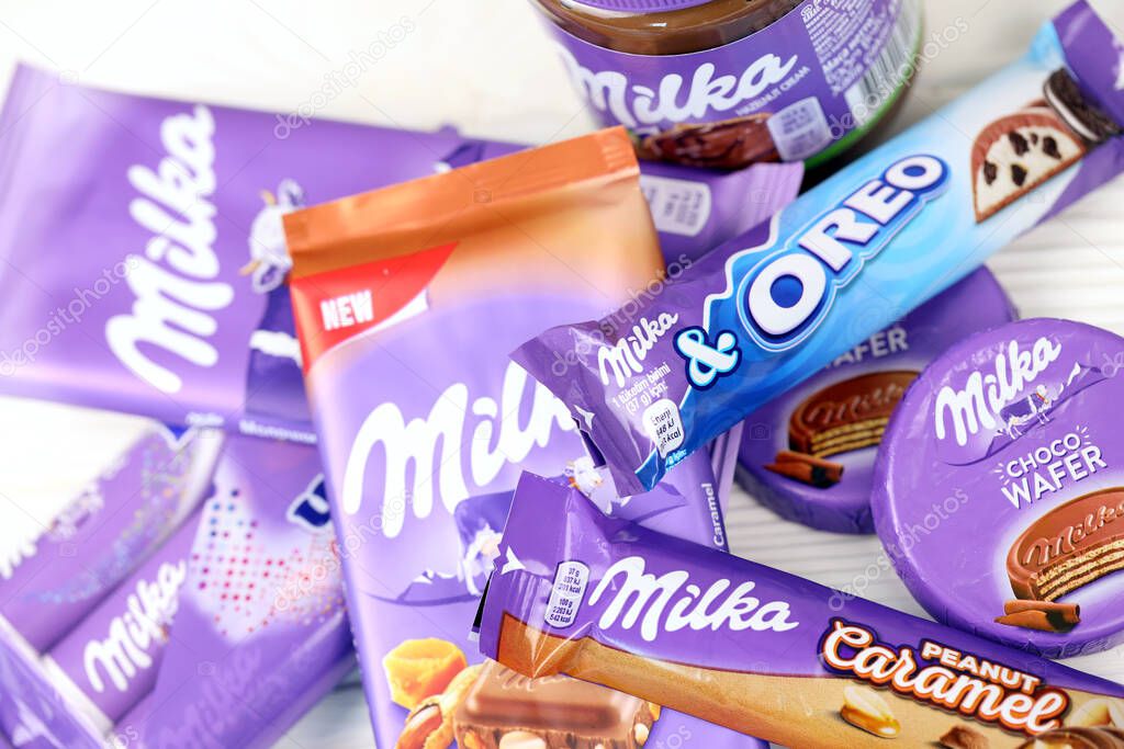 KHARKOV, UKRAINE - JULY 2, 2021: Milka chocolate products with classical lilac color wrapping design on white wooden table