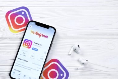 KHARKOV, UKRAINE - 5 Mart 2021: Instagram simgesi ve uygulaması iPhone 12 'deki profosyonel ekranda beyaz ahşap masadaki hava podları profosyoneli