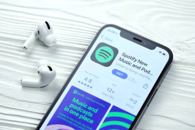 KHARKOV, UKRAINE - 5 Mart 2021: iPhone 12 'deki Uygulama mağazasından gelen simge ve uygulamayı beyaz ahşap masadaki uçak podları profesyoneli ile birlikte ekranda şımart