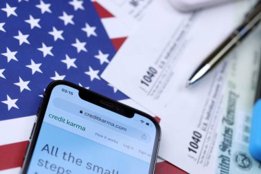 KHARKOV, UKRAINE - 5 Mart 2021: ABD bayrağında 1040 ve w-2 kağıt vergi formlarıyla iPhone 12 profesyonel ekranda kredi karması web sitesi