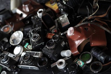 KHARKOV, UKRAINE - 27 Nisan 2021: Fotoğraf makineleri ve fotoğrafçı karanlık odasındaki siyah ahşap masada eski bir fotoğraf makinesi. Sovyetler Birliği zamanından fotoğraf malzemeleri.