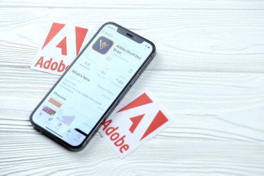 KHARKOV, UKRAINE - 5 Mart 2021: Adobe illüstratör simgesi ve uygulaması iPhone 12 'den beyaz ahşap masadaki profesyonel ekranda