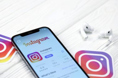 KHARKOV, UKRAINE - 5 Mart 2021: Instagram simgesi ve uygulaması iPhone 12 'deki profosyonel ekranda beyaz ahşap masadaki hava podları profosyoneli