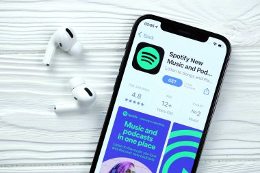 KHARKOV, UKRAINE - 5 Mart 2021: iPhone 12 'deki Uygulama mağazasından gelen simge ve uygulamayı beyaz ahşap masadaki uçak podları profesyoneli ile birlikte ekranda şımart