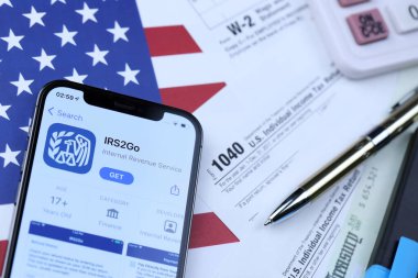 KHARKOV, UKRAINE - 5 Mart 2021: IRS2GO uygulaması iPhone 12 profesyonel ekranda 1040 ve W-2 ABD bayrağında kağıt vergi formları