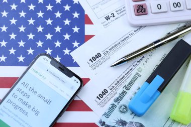 KHARKOV, UKRAINE - 5 Mart 2021: ABD bayrağında 1040 ve w-2 kağıt vergi formlarıyla iPhone 12 profesyonel ekranda kredi karması web sitesi