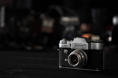 KHARKOV, UKRAINE - 27 Nisan 2021: Zenit 3 m fotoğraf makinesi ve fotoğrafçı karanlık odasındaki siyah ahşap masada eski bir fotoğraf makinesi. Sovyetler Birliği zamanından fotoğraf malzemeleri.