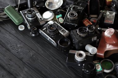 KHARKOV, UKRAINE - 27 Nisan 2021: Fotoğraf makineleri ve fotoğrafçı karanlık odasındaki siyah ahşap masada eski bir fotoğraf makinesi. Sovyetler Birliği zamanından fotoğraf malzemeleri.
